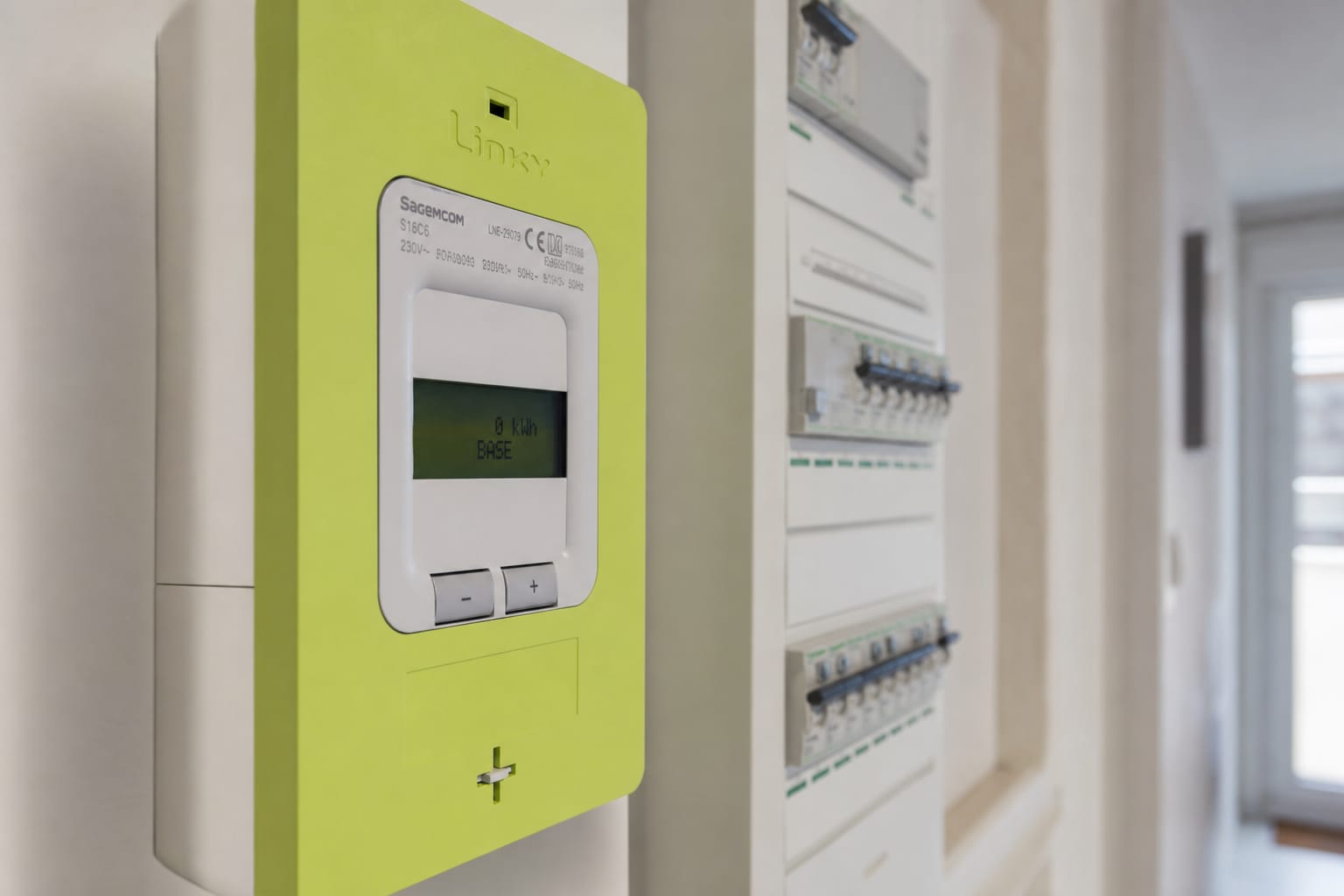 Tableau électrique et compteur Linky dans un couloir de maison, écran affichant la consommation