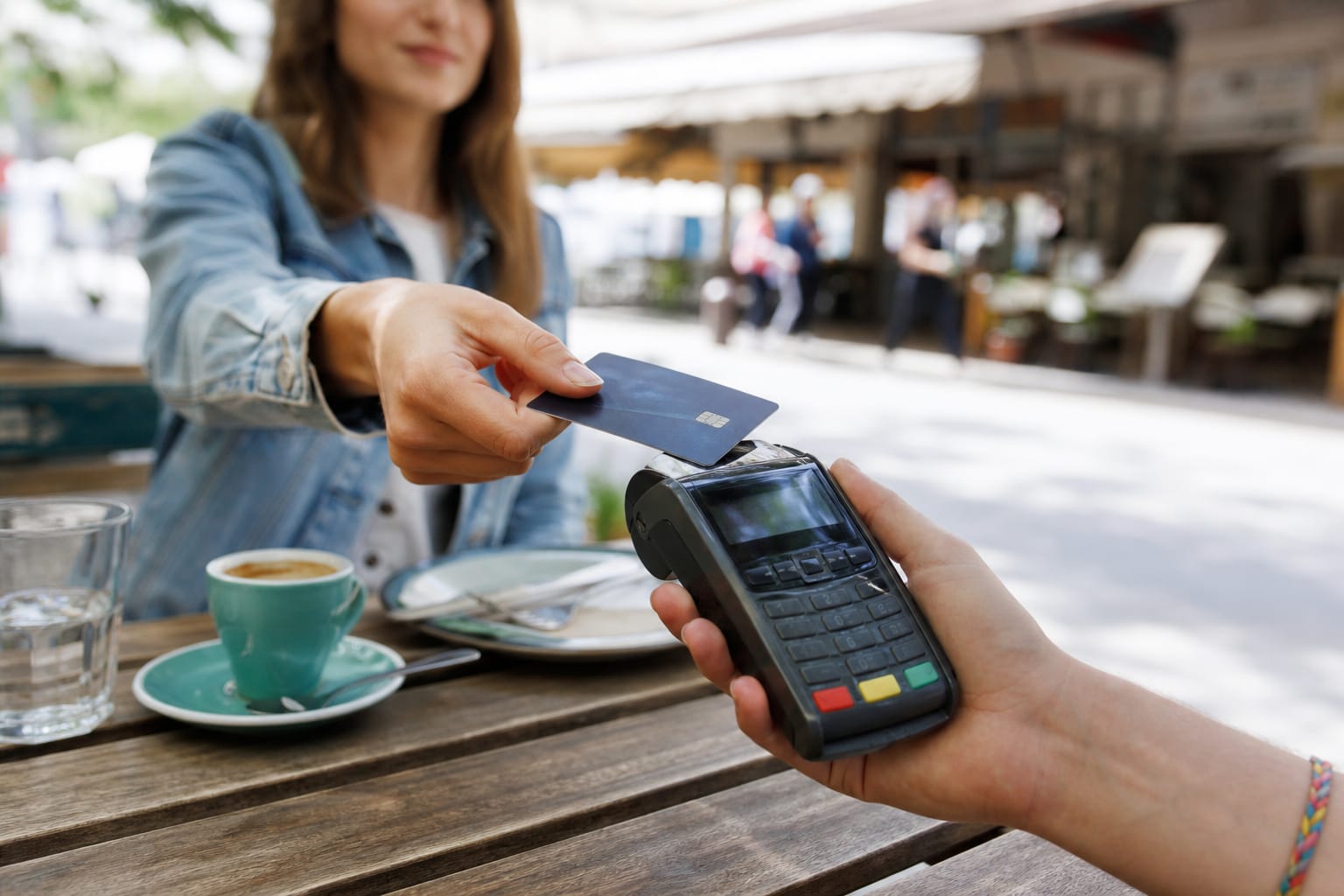 Main tenant une carte bancaire devant un terminal de paiement dans un café à l'étranger, message d'erreur affiché