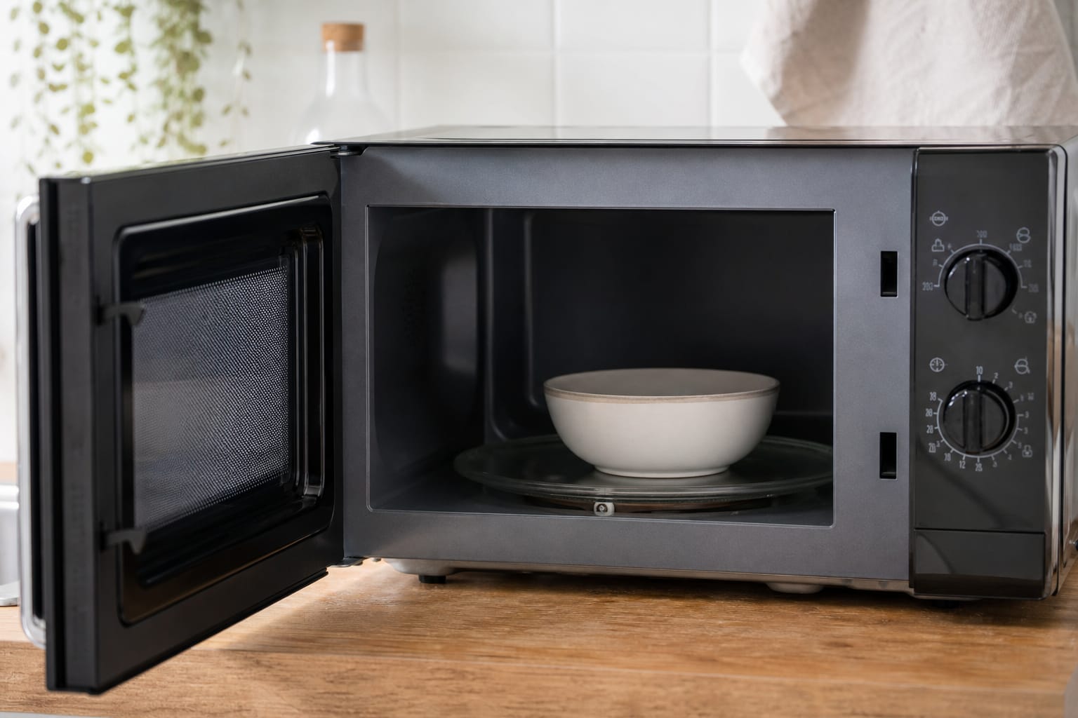 Micro-ondes ouvert sur un plan de travail de cuisine, plateau tournant visible, bol posé à l'intérieur
