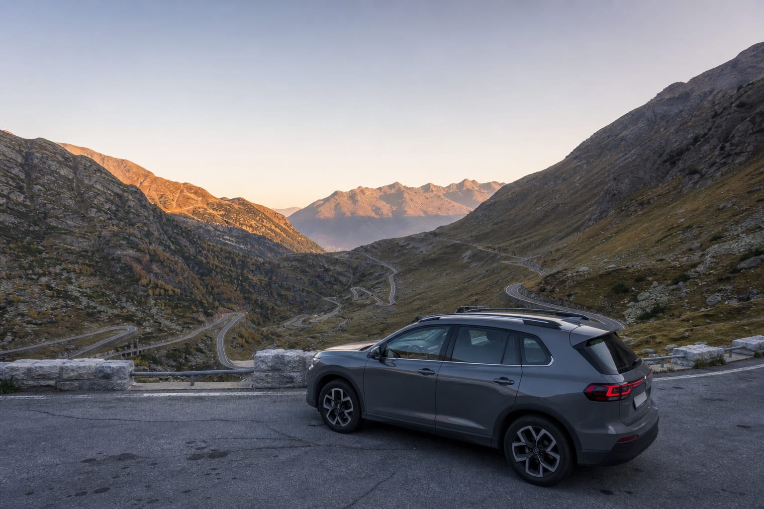 Voiture garée sur une aire de repos en montagne, route en épingles visible en arrière-plan, capot fermé